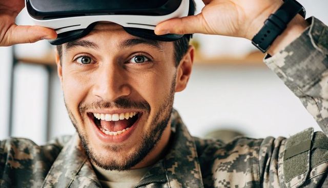 Smiling soldier lifting vr headset while wearing camouflage uniform and smartwatch