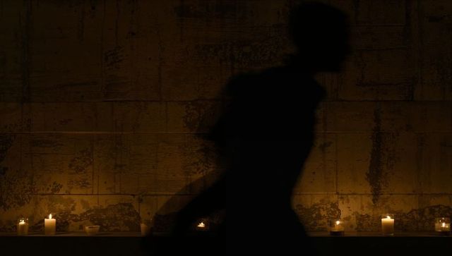 Silhouette in candlelit passage with vintage stone walls