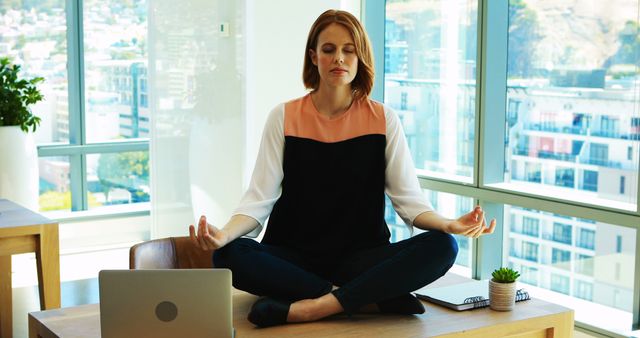 Young Professional Woman Meditating on Office Desk in Busy Workspace - Download Free Stock Images Pikwizard.com