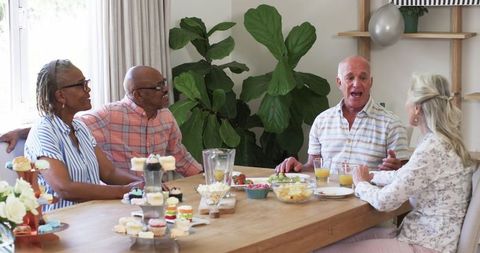 Senior Friends Conversing Over Snacks at Home