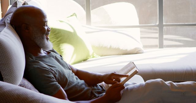 Middle-aged Man Relaxing on Sofa Reading eBook in Natural Light - Download Free Stock Images Pikwizard.com