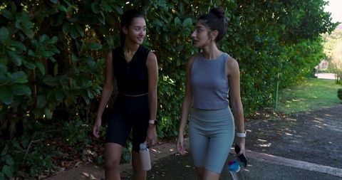 Active Female Friends Walking in Park with Water Bottles