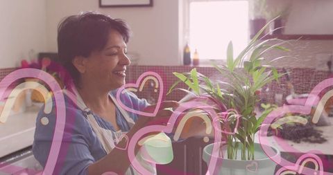 Smiling Woman Watering Healthy Indoor Plant at Home Kitchen Counter