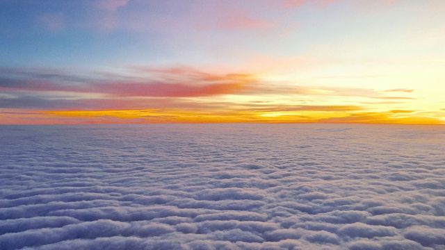 Capturing the serene beauty of a sunset above a layer of clouds is perfect for travel blogs, nature documentaries, or serene-themed designs. The soft light and colorful sky evoke feelings of calmness and wonder. Ideal for background images or inspirational quotations.
