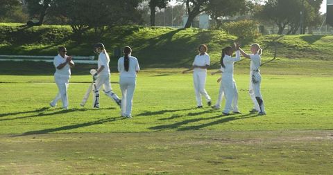 Female Cricketers Celebrating on Field During Sunny Day
