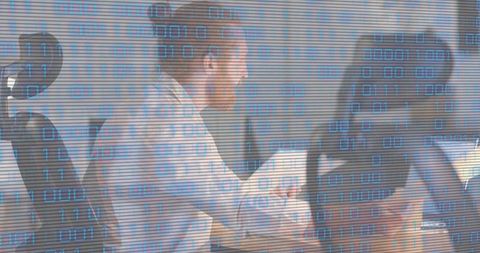 Business team collaborating on laptops and papers with binary code overlay