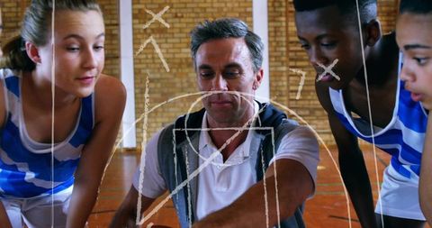 Youth basketball coach drawing offensive play on plexiglass board during team huddle