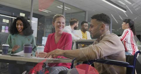 Diverse team collaborating in modern open office around table with coffee and documents