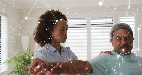 Home caregiver assisting senior man stretching arm for physical therapy and mobility support