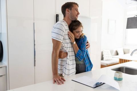 Happy couple embracing in modern kitchen review contract