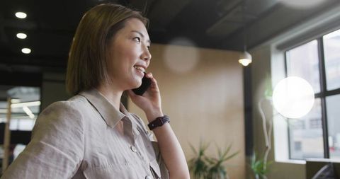 Asian Professional Communicating on Smartphone in Modern Office