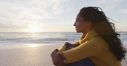 Contemplative Woman Enveloped in Sunset on Serene Beach