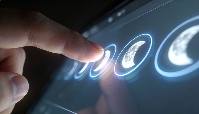 Tapping Glowing Moon Phase Icons on Touchscreen Tablet Using Fingertip