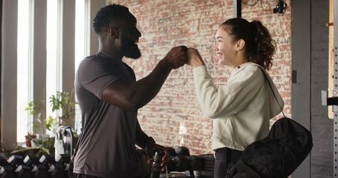 Diverse Trainer and Client Celebrating Gym Achievement with Fist Bump