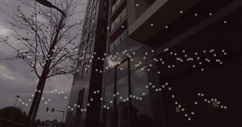 Reflective glass facade reflecting moody sky with digital glitch overlay and urban tree