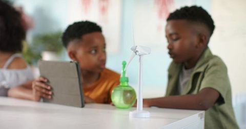 African american children examining tabletop wind turbine during stem learning with tablet