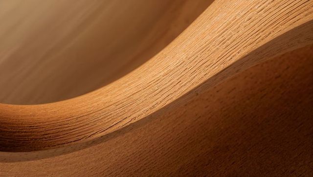 Curved laminated wood macro showing layered edge and warm grain texture