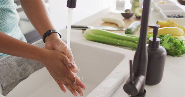 Midsection of african american woman washing hands in sink in kitchen. domestic lifestyle, spending free time at home.
