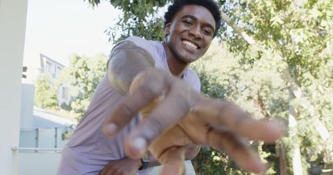 Joyful Young Adult Male Outdoors Reaching Toward Camera