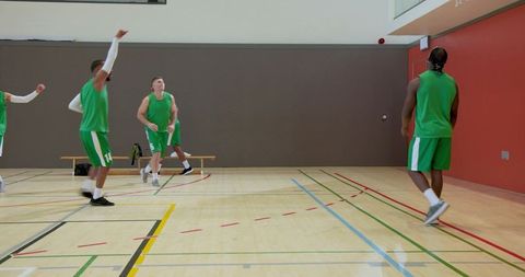 Male basketball team entering indoor court dribbling huddling practicing teamwork