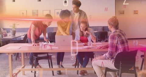Young creative team collaborating around laptop in modern coworking space