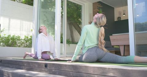 Friends practicing yoga on home deck doing morning stretches together for wellness