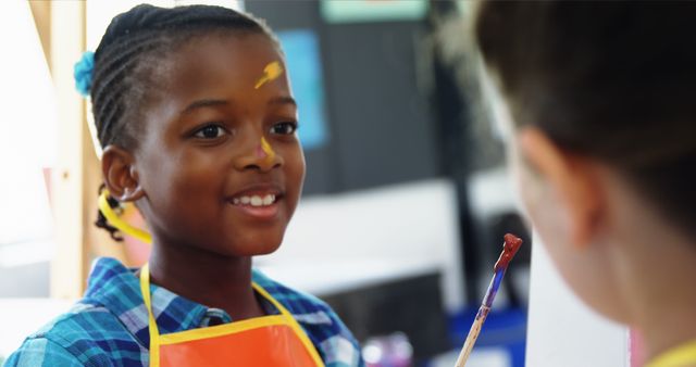 Young African American girl enjoying painting in art class. Suitable for use in educational content, creativity campaigns, and promotional materials for children's art programs or schools.