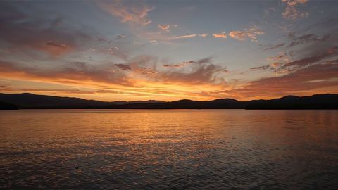 Serene Sunset over Calm Mountain Lake with Vibrant Sky Reflection