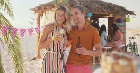 Happy Couple Enjoying Tropical Drinks at Beachside Tiki Bar