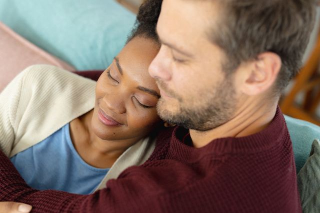 Diverse couple embracing and sitting in living room. Spending quality time together at home concept.