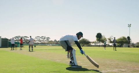 Asian indian batsman sprinting and diving to play shot on sunlit community cricket pitch