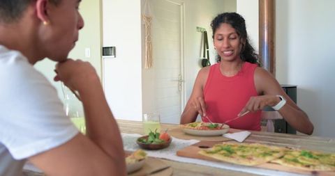 African couple sharing relaxed lunch with flatbread and salad at wooden table