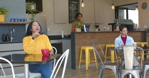 Woman checking smartwatch while enjoying coffee in bright modern cafe with barista