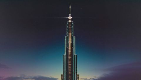Slender skyscraper piercing twilight sky with illuminated spire and vertical led lines