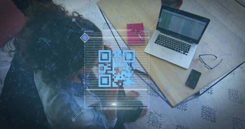 Overhead scene of woman studying with laptop red notebook QR code overlay for remote work