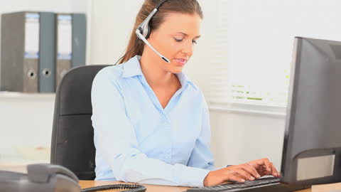Professional Office Worker Typing at Desk with Headset