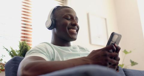 Smiling Man Relaxing with Smartphone and Headphones Indoors