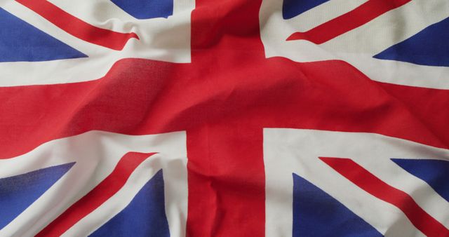 Displaying a close-up of a wrinkled Union Jack, the flag of the United Kingdom. This could be used in projects related to British culture, patriotism, or national holidays. Its detailed view of the fabric and the iconic red, white, and blue colors make it suitable for educational content, travel blogs, promotional material, or as a background element.
