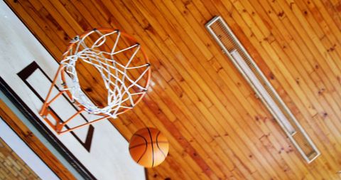Basketball Near Hoop in Indoor Gymnasium Capturing Game Moment