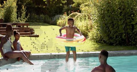 Family enjoying backyard pool, father guiding boy with inflatable ring, summer fun