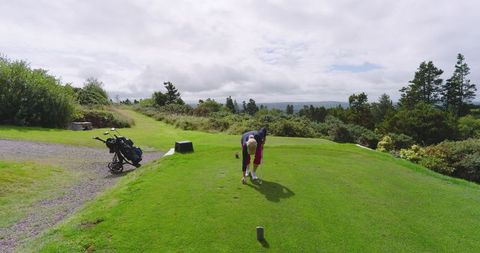 Senior woman preparing tee shot on scenic golf course
