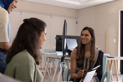 Diverse team collaborating in bright modern office with south asian coworker wearing kurta