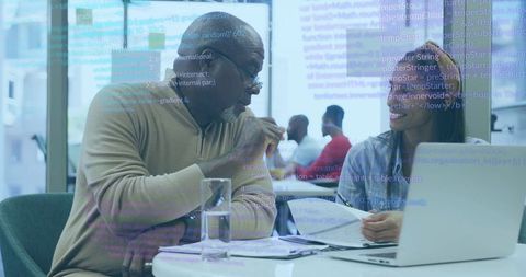 Developer Explaining Code to Colleague During Collaborative Laptop Review in Modern Office