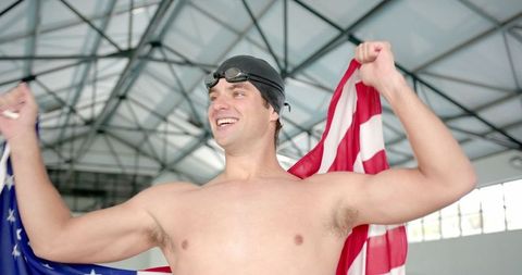 Joyful Male Swimmer Holding American Flag in Indoor Pool