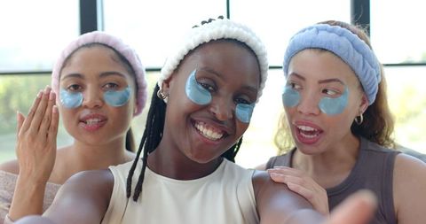 Diverse women enjoying at-home spa day wearing hydrogel under-eye patches and headbands