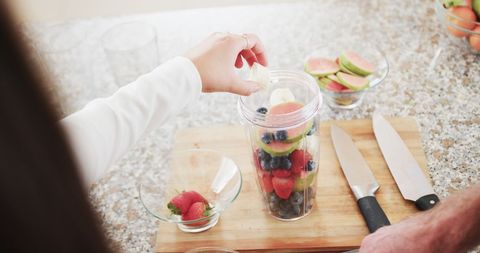 Couple Preparing Fresh Fruit Smoothie in Sunny Kitchen