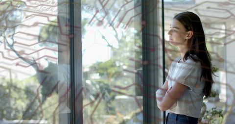 Young Woman Gazing Through Window with Circuit Hex Overlay and Sunlit Garden Reflection