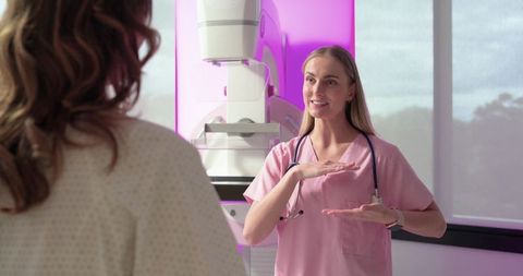 Female technologist explaining mammography procedure to patient in breast imaging clinic