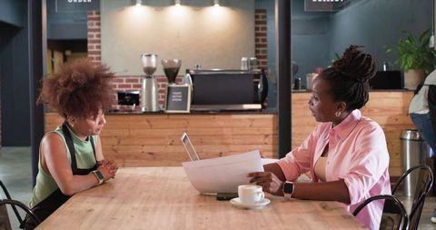 Manager reviewing documents with barista during cafe meeting
