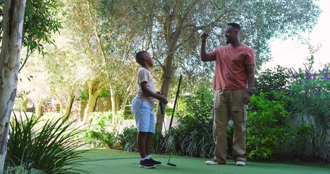 Father and Son Practicing Putting on Garden Green